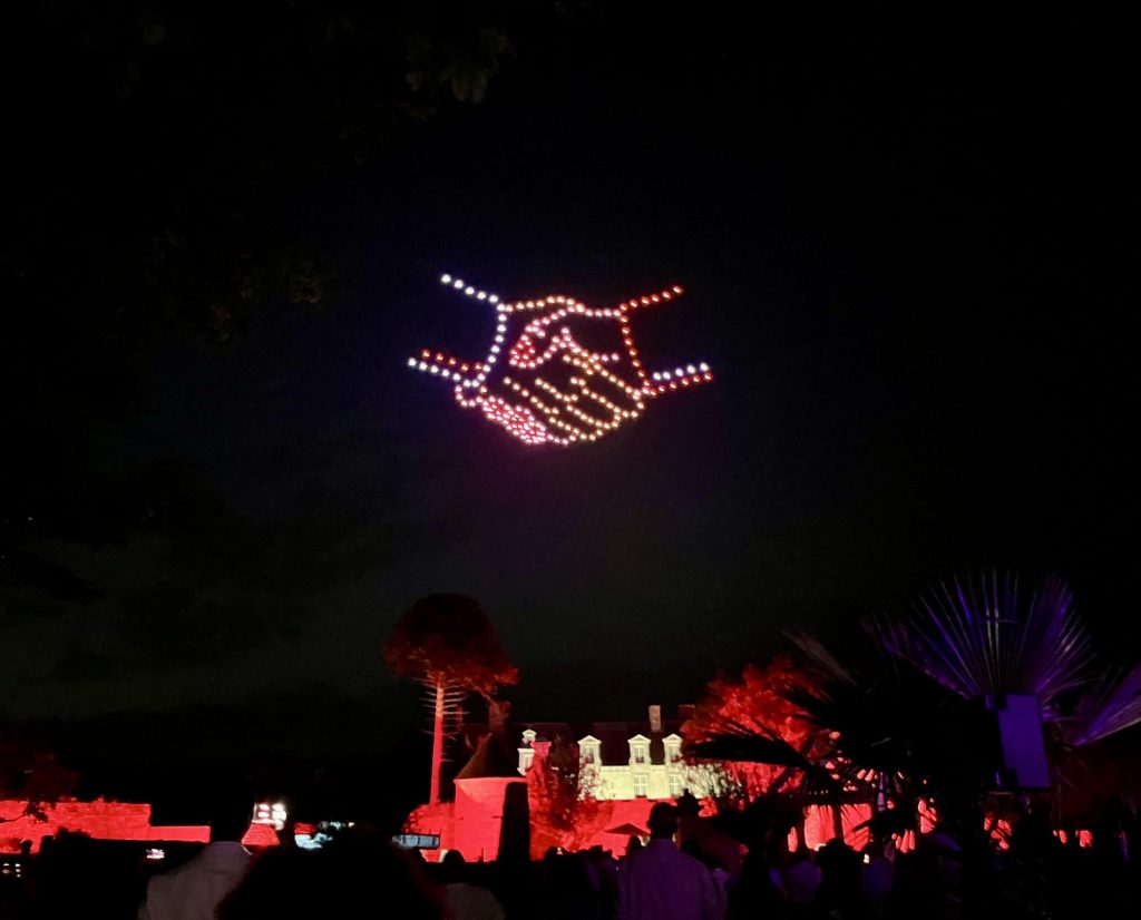 Illuminated drone show depicting two hands shaking at a corporate event